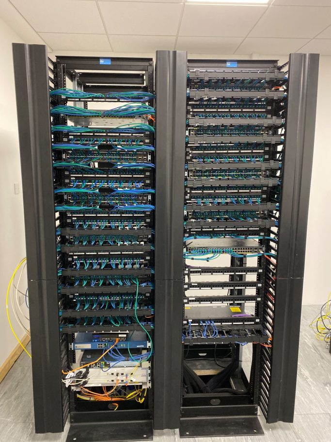 Small office comms room Two server racks filled with networking equipment and cables.